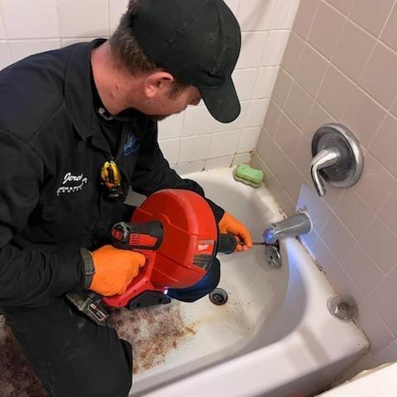 Technician feeding a drain cable into a bathtub waste line