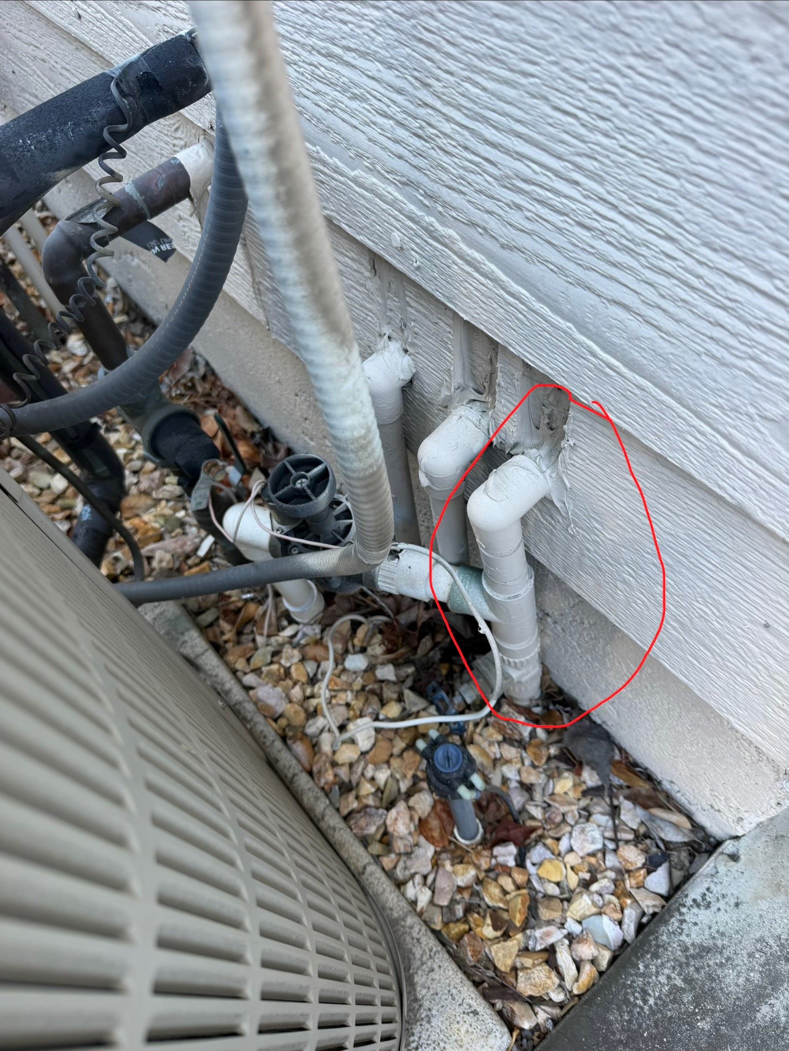 PVC condensate drain piping beside an outdoor HVAC unit