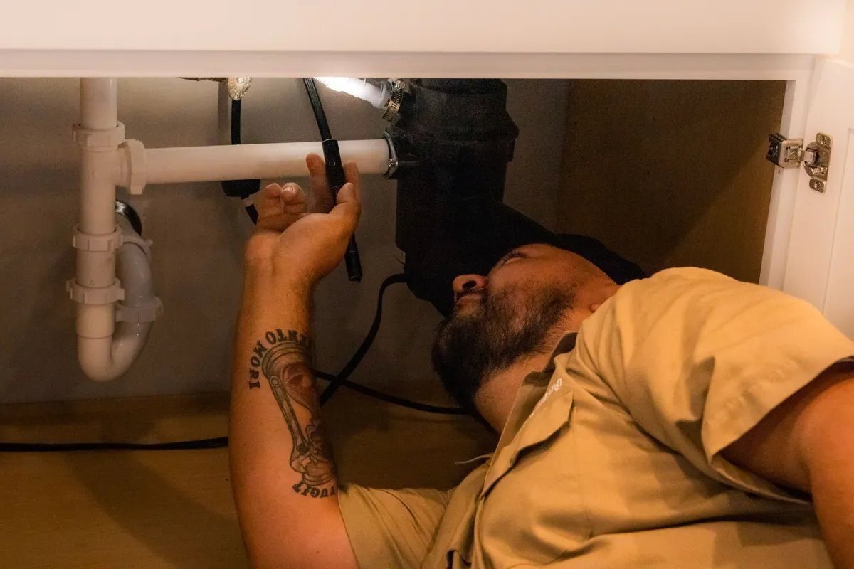 Plumber repairing the drain under a sink