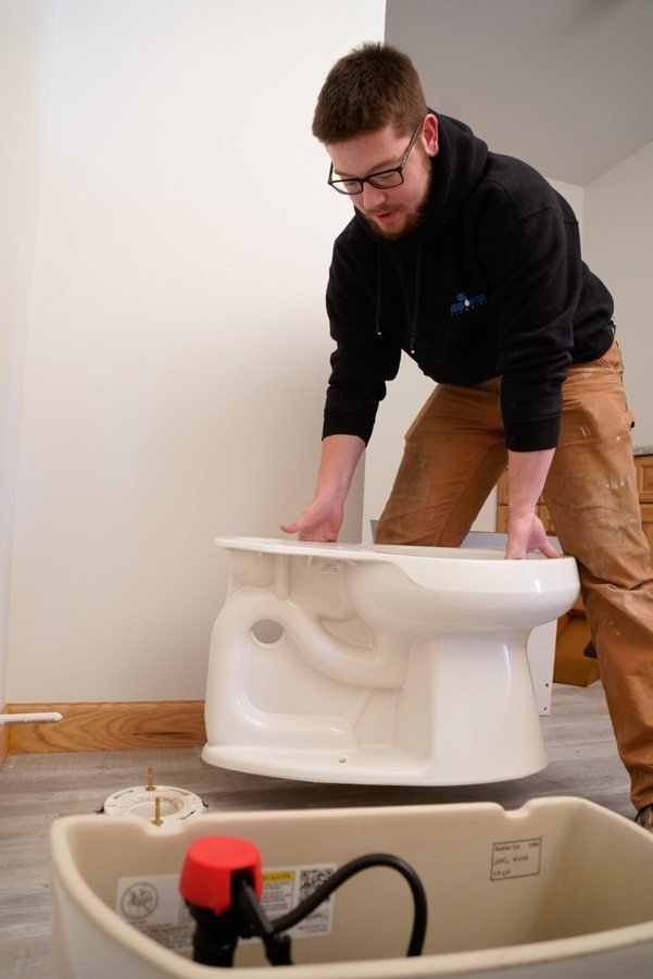 Technician carrying a toilet into position