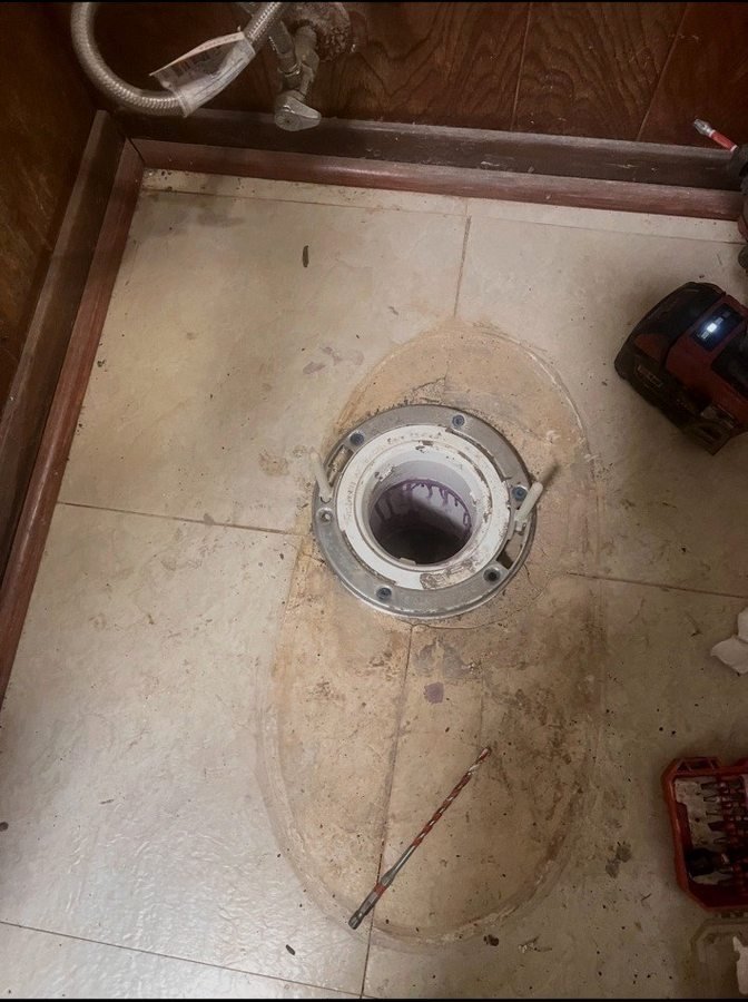 Toilet flange visible at the finished floor before a toilet is installed