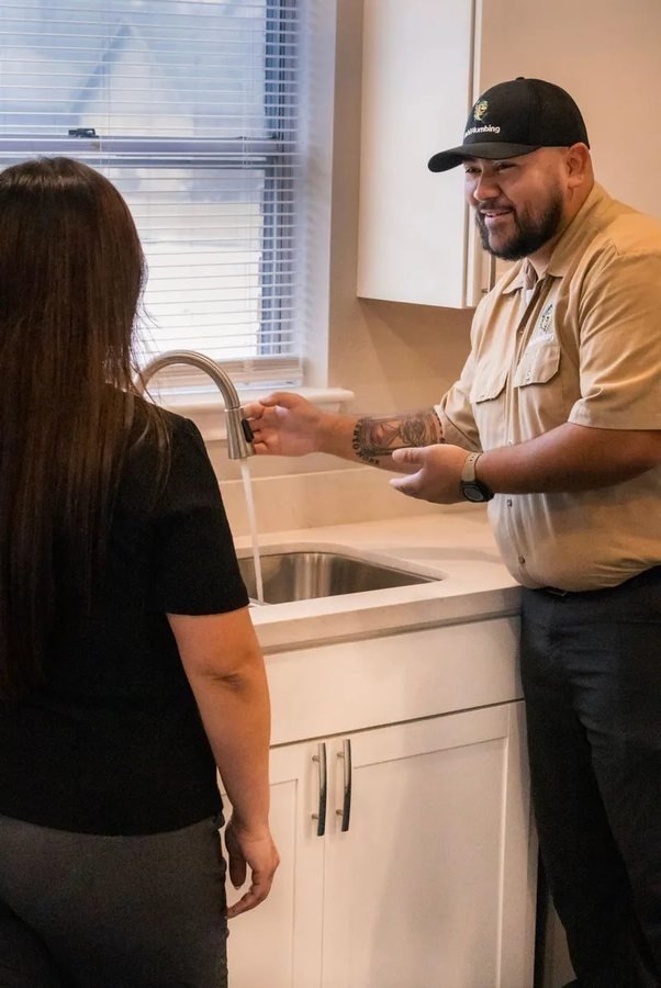 Plumber checking a kitchen faucet with a homeowner