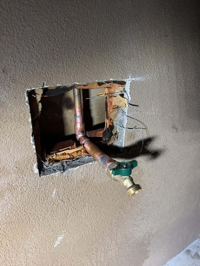 Opened wall exposing water piping