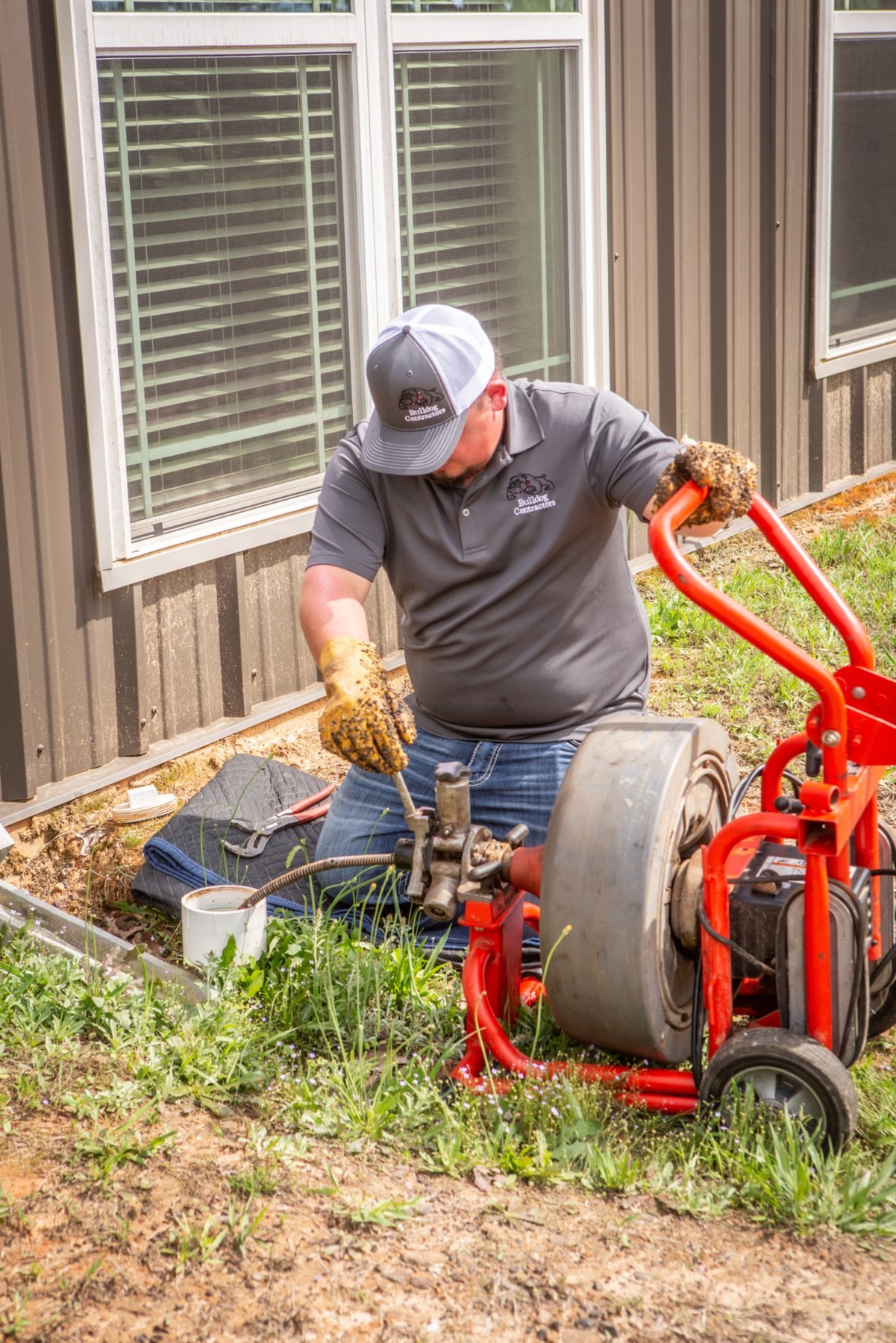 Technician operating a drain-cleaning cable machine outside